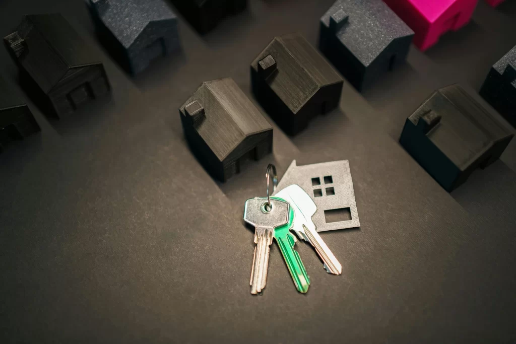 House keys with model homes representing self-managing vs hiring a property manager for rental properties